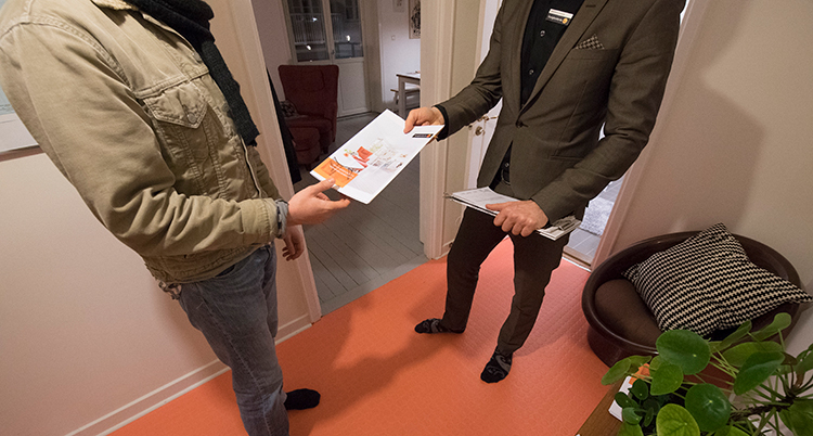 De står i en lägenhet som är till salu och håller i papper.
