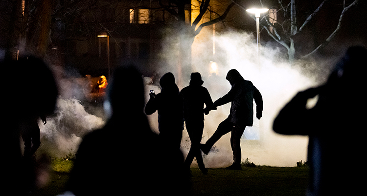 Tre personer syns som siluetter i natten. En sparkar med foten.