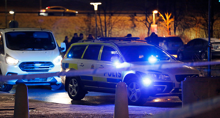 Två polisbilar och en avspärrning i ett mörkt område utomhus.