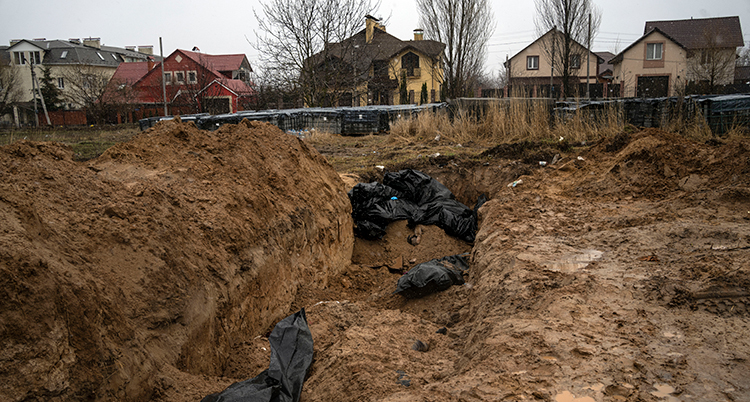 En uppgrävd stor grop i marken med kroppar i svarta säckar.