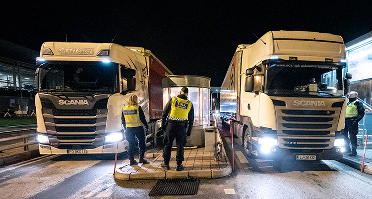Två poliser franför två långtradare.