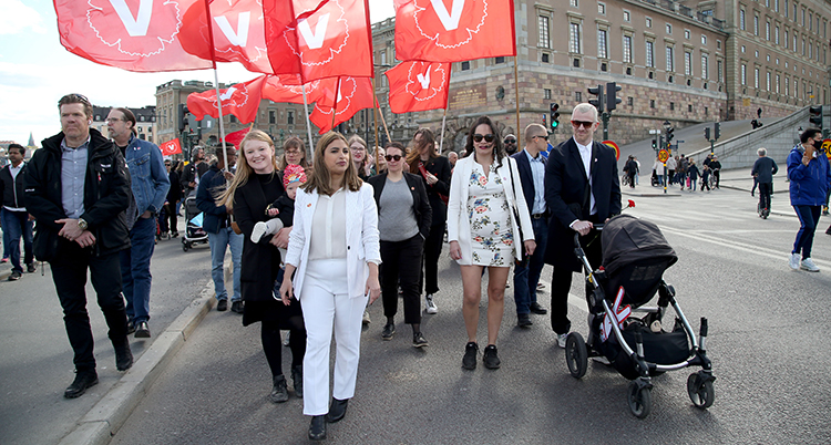 Hon går längst fram i demonstrationen. Folk bakom bär röda flaggor.