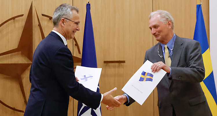 Axel är till höger. Han tar i hand med Jens. Axel har ett papper som han ska lämna till Jens.