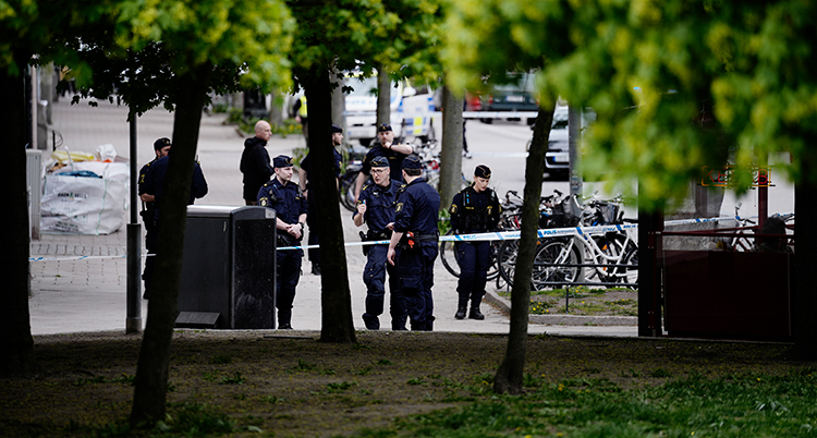 Poliser bakom en avspärrning på platsen.
