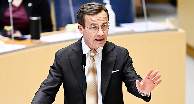 Ulf Kristersson står i riksdagens talarstol och pratar.