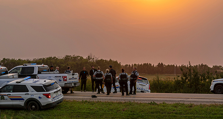 Det börjar bli kväll. Flera poliser och polisbilar är samlade på en väg.