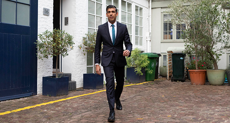 Rishi Sunak går ut från ett hus.