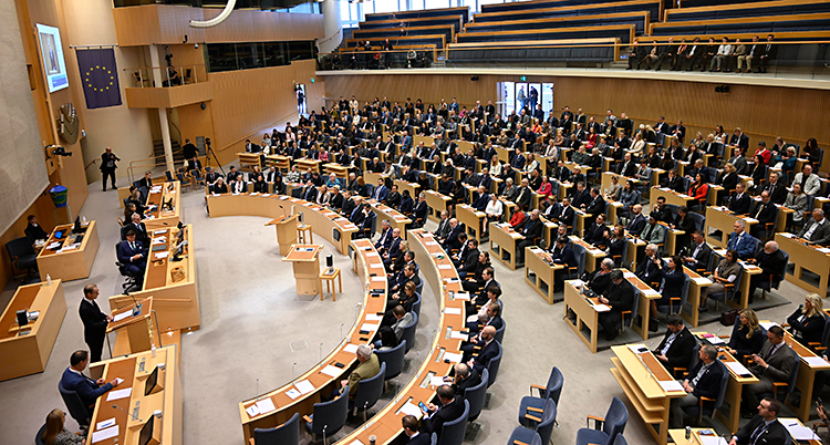 En stor sal där politiker sitter i bänkar.
