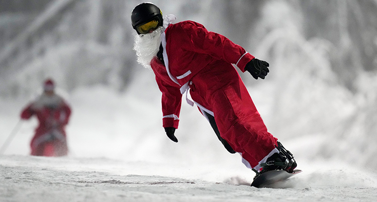 En tomte åker snowboard. De ryker av snö bakom