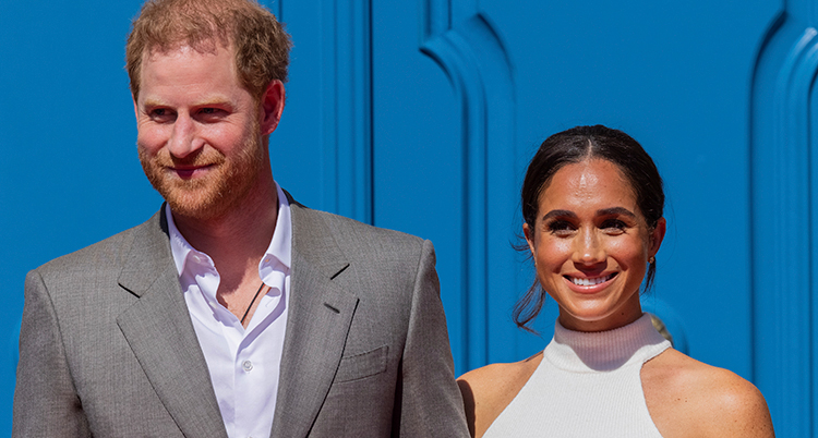 Harry och Meghan står bredvid varandra och ler.