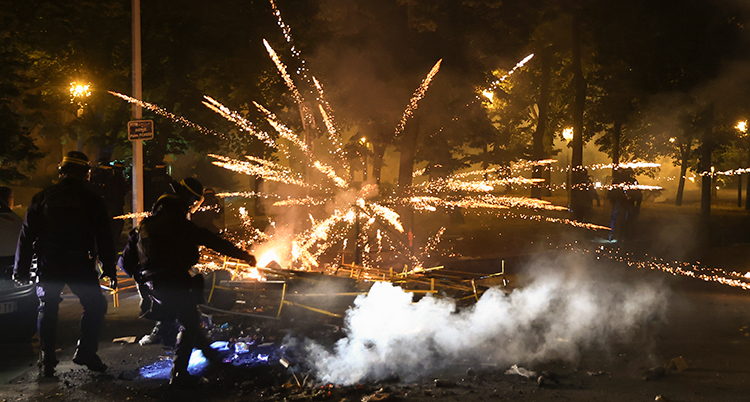 Fyrverkeri exploderar vid poliser på gatan på natten.