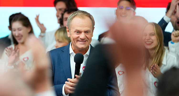 Donald Tusk ser glad ut. Flera glada människor står runt honom.