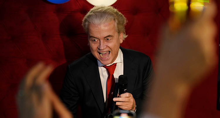 Han är glad. Han har en mikrofon. Människor klappar händerna runt honom.