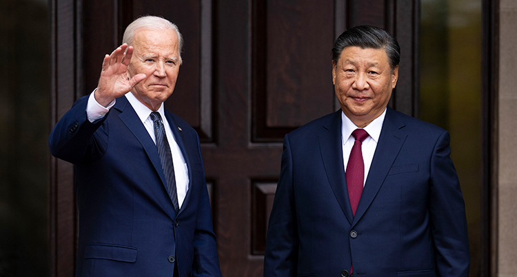 De står bredvid varandra framför en port. Biden vinkar.