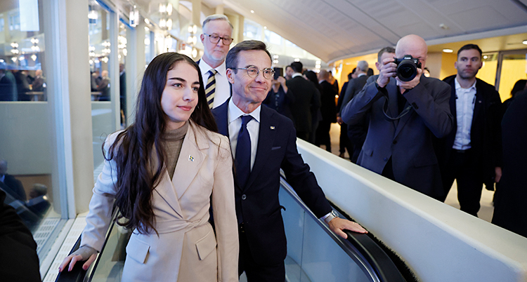 Romina Pourmokhtari åker upp för en rulltrappa. Bakom henne står Ulf Kristersson och Johan Pehrson.