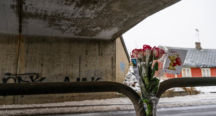 En bukett blommor sitter på ett staket vid en väg under en tunnel.