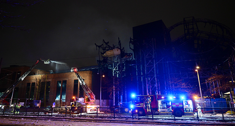 Det är mörkt ute. Brandbilar och brandmän står vid huset.