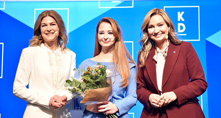 De tre står bredvid varandra. Kvinnan i mitten håller i en blombukett.