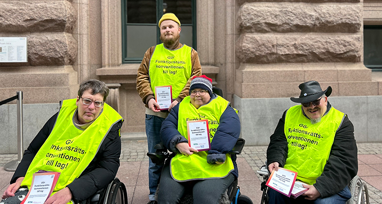 De har gula västar på sig. Tre av dem använder rullstol.