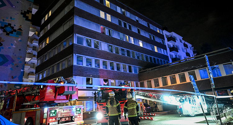 Avspärrningar framför ett hus med flera våningar.