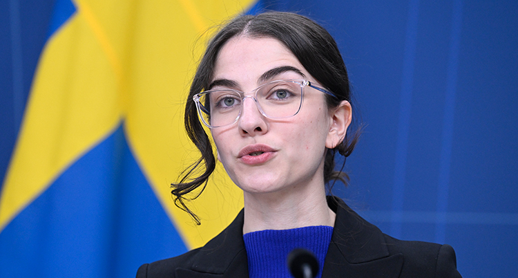 Hon pratar framför en svensk flagga.