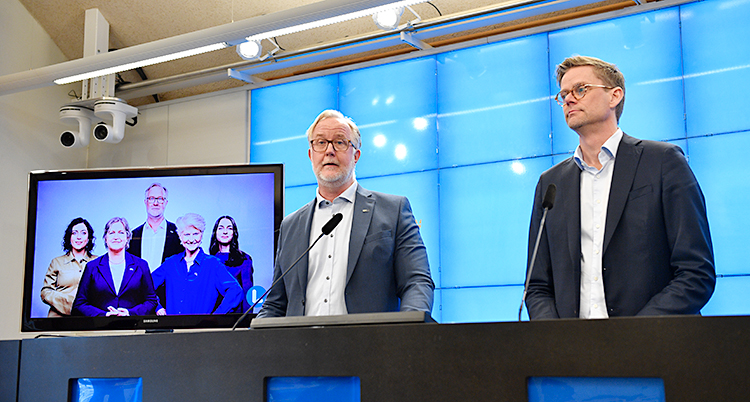 Två män står och pratar på ett möte för journalister.