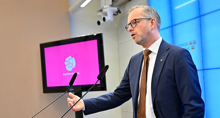 Damberg talar. Bakom honom finns en skärm där det står Socialdemokraterna.