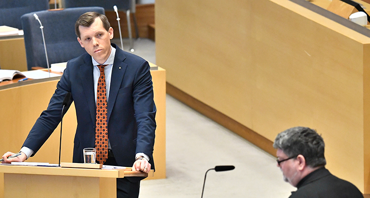 Hultberg står i talarstolen och tittar på en annan man som talar.