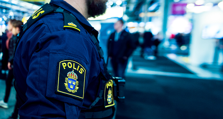 En polis syns i förgrunden. Bakom syns människor som går.