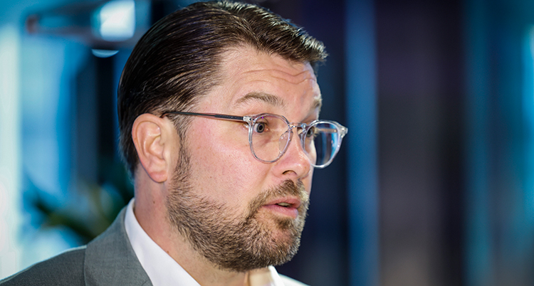 Porträtt från sidan. Han har skägg och glasögon.