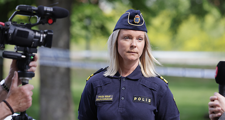 Hon står utomhus och blir intervjuad av journalister.