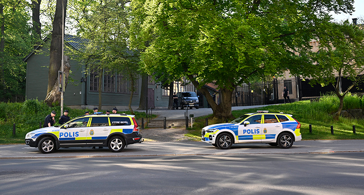 Två bilar står utanför ett stort hus.