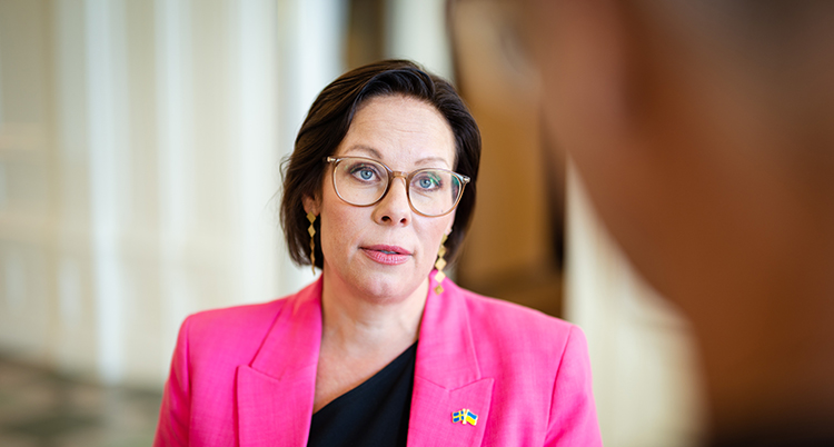 Hon har rosa kavaj och glasögon.