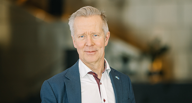 Han har grått hår och vit skjorta.