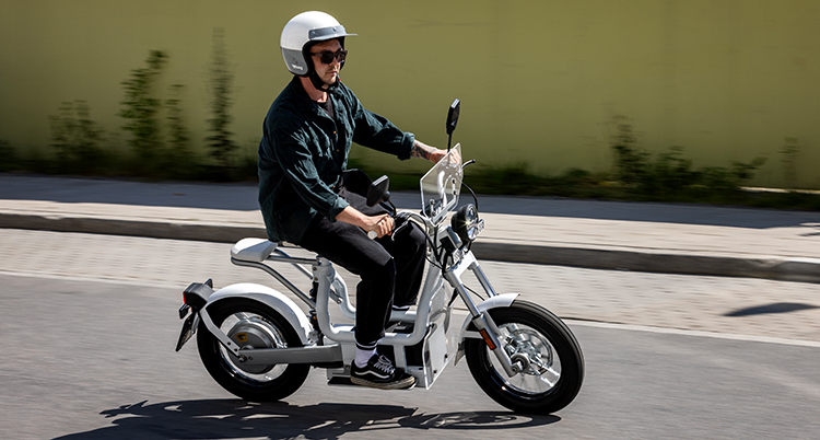 En man med hjälm kör en elmoped.