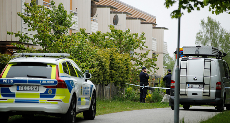 Polisbilar står utanför ett hus med flera lägenheter.