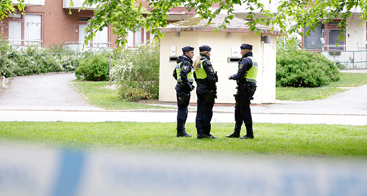 Poliser bakom en avspärrning.