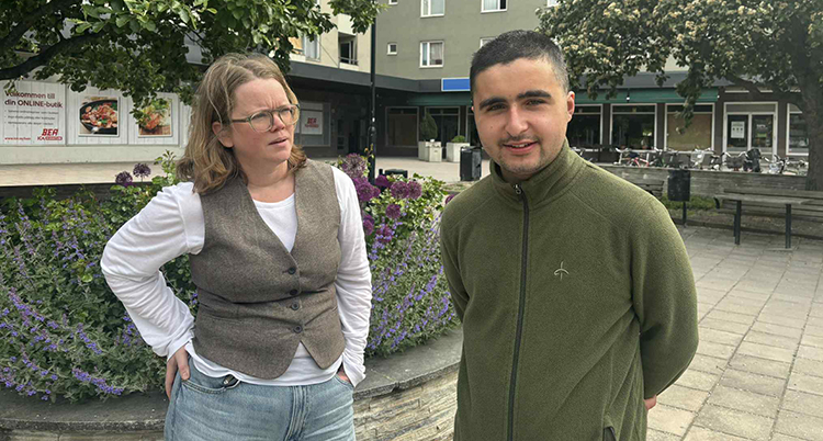Han står längst fram. Hon tittar på honom.