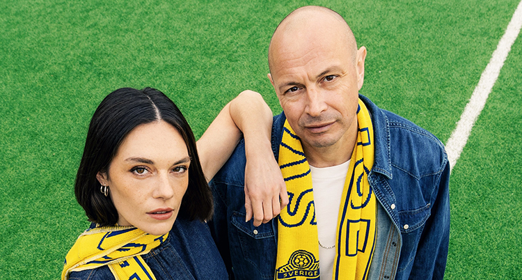De står på en plan för fotboll. De har gula svenska halsdukar.