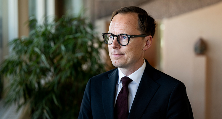 Han har kostym och glasögon.