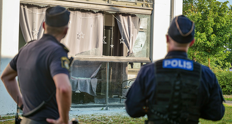Poliser tittar på en trasig inglasad balkong.