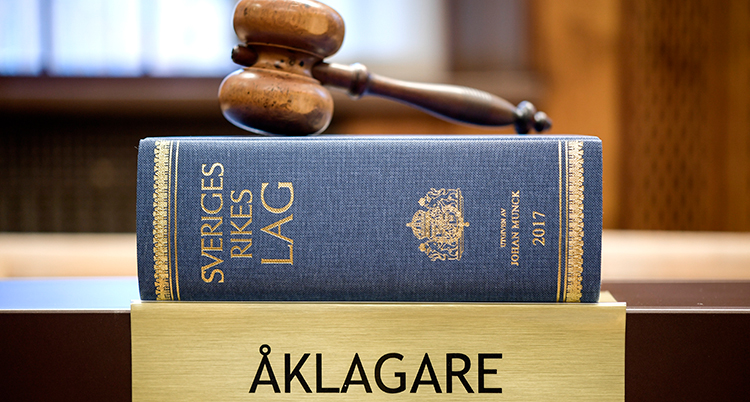 En klubba som man slår i bordet med, en tjcok bok och en skylt där det står åklagare på.