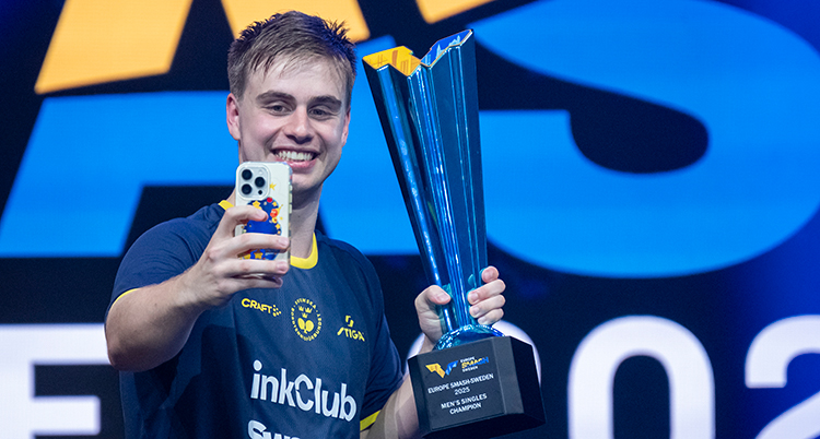 Han håller en pokal. Han tar en bild på sig själv.