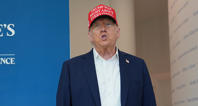 Donald Trump står med kavaj och en röd keps. På kepsen står det Trump was right about everything.