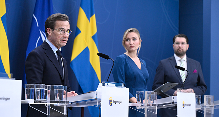De står på rad med mikrofoner framför sig.