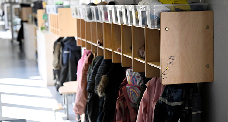 Hyllor för kläder och kläder som hänger på krokar på en förskola.