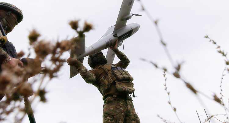 En soldat håller en drönare som ser ut som ett litet flygplan.