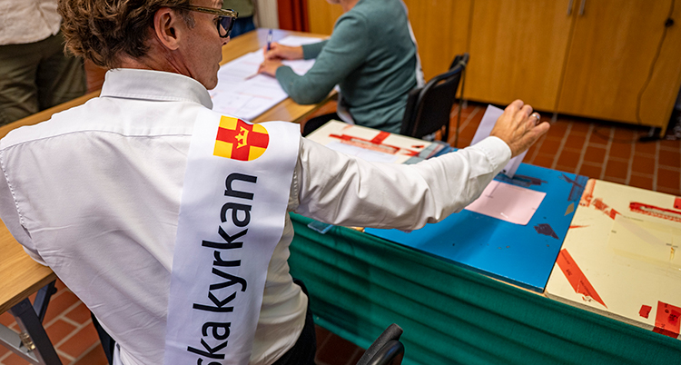 En man som jobbar som röstmottagare lägger ner en röst i urnan.