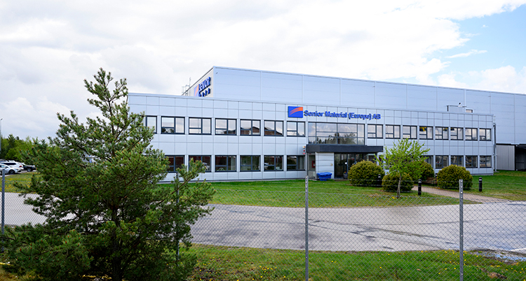 Fabriken syns utifrån. Företagets logga sitter på en av väggarna.