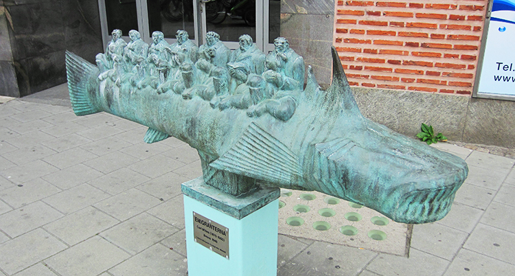 En grön staty med en fisk med små personer på.